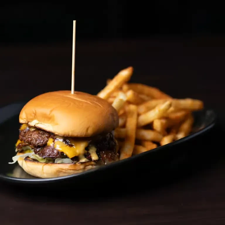 Two-patty cheeseburger with melted cheese, lettuce, pickles, and golden fries.