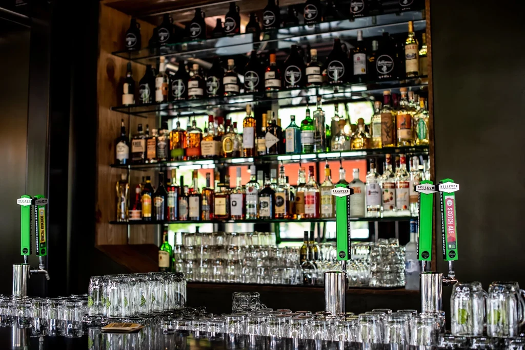 Bar area with liquor bottles, Bellevue taps, and stacked drinking glasses.