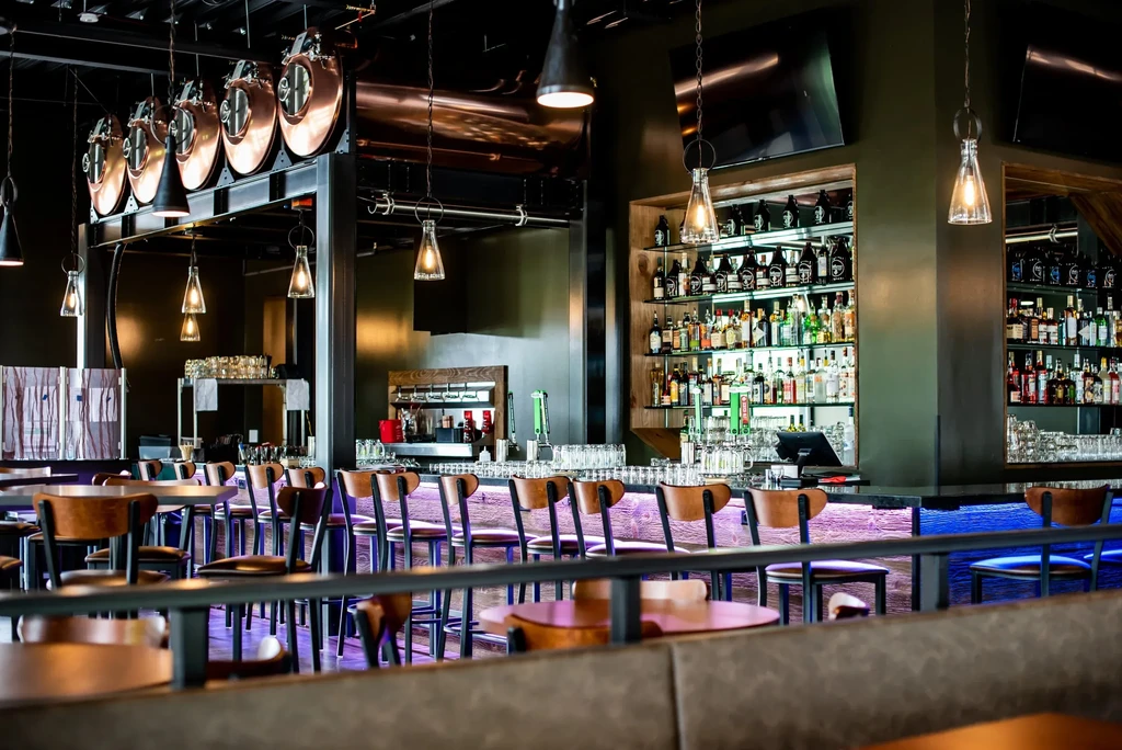 Modern bar and restaurant with tiered liquor bottles and copper accents.