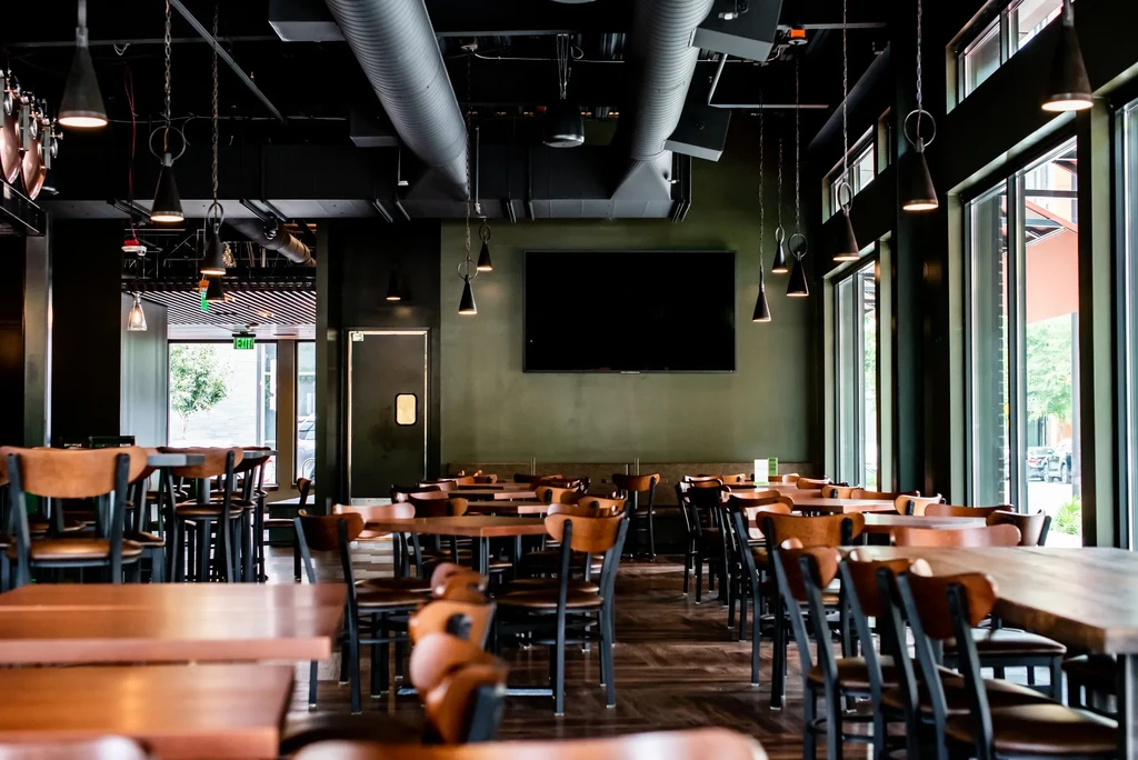 Empty modern restaurant interior with olive-green walls and industrial design.