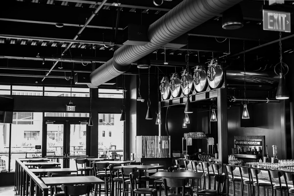 Modern industrial restaurant interior with brewing tanks and seating.