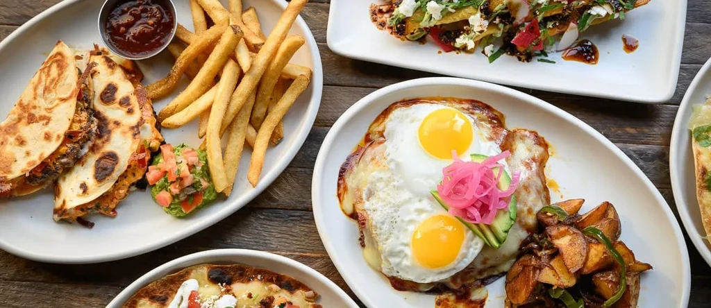 Top-down view of a rustic table with four diverse food dishes.