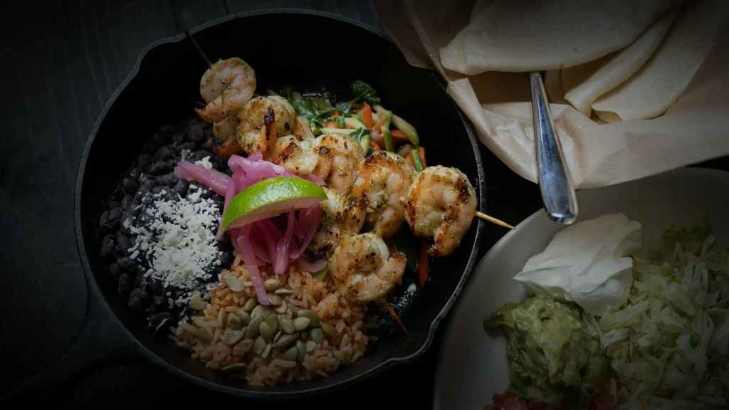 Grilled shrimp and vegetable skillet with rice, tortillas, and dips.