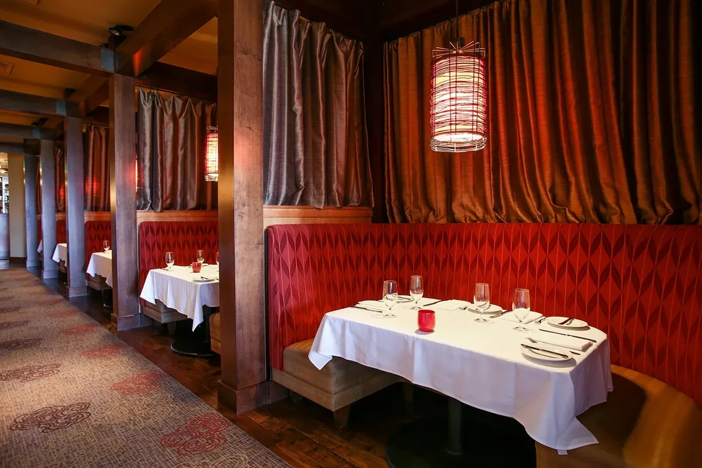 Empty upscale restaurant with private red booths and warm lighting.