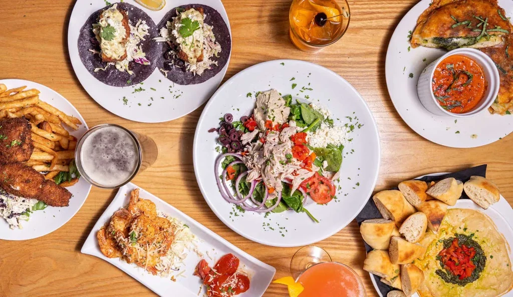 Overhead flat lay of various dishes and drinks on a wooden table.