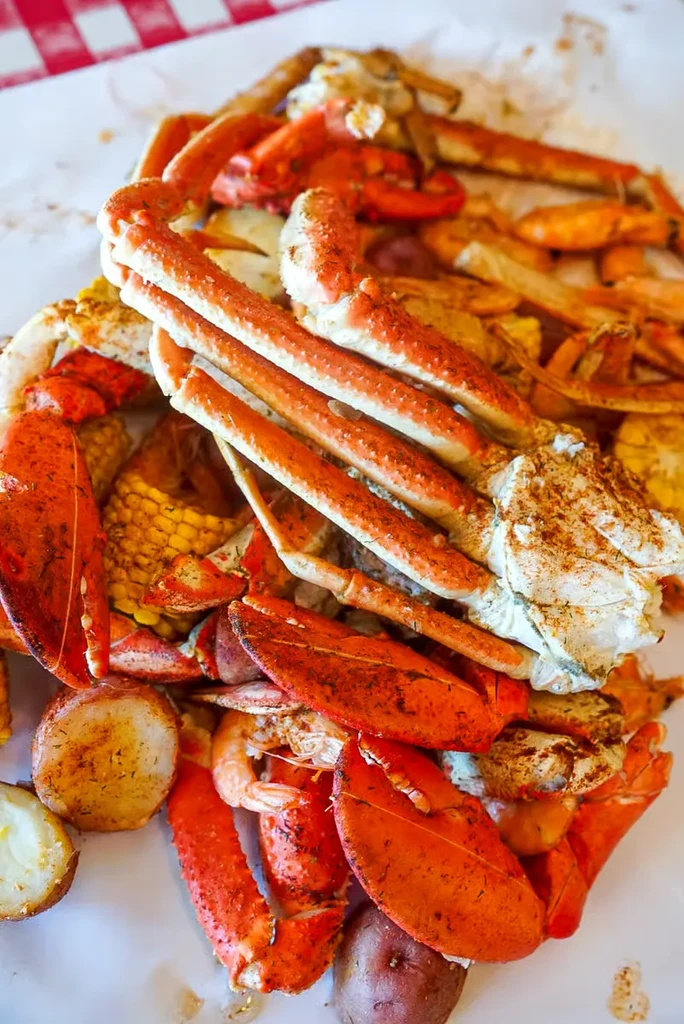 Close-up of a seafood boil with crab, lobster, shrimp, corn, potatoes.