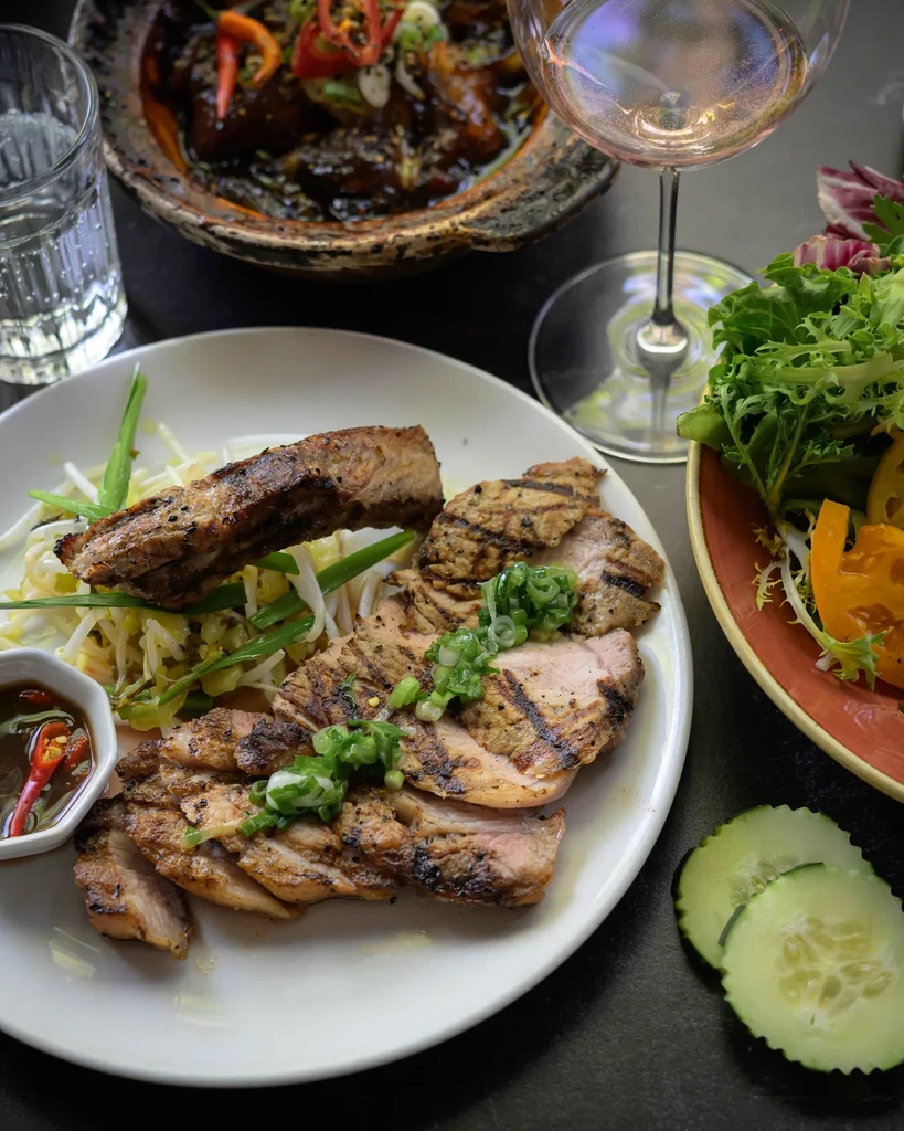 Close-up of grilled meat, bean sprouts, salad, sauce, and drinks.