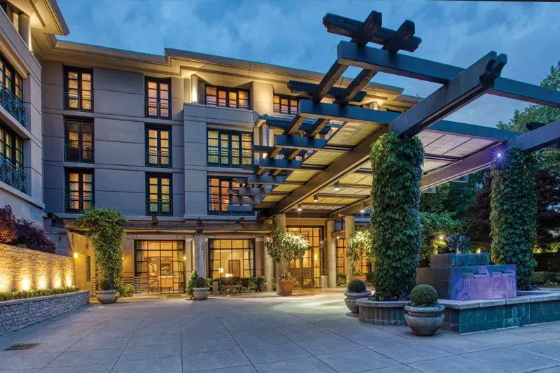 Building entrance at twilight with ivy-covered columns and a purple fountain.