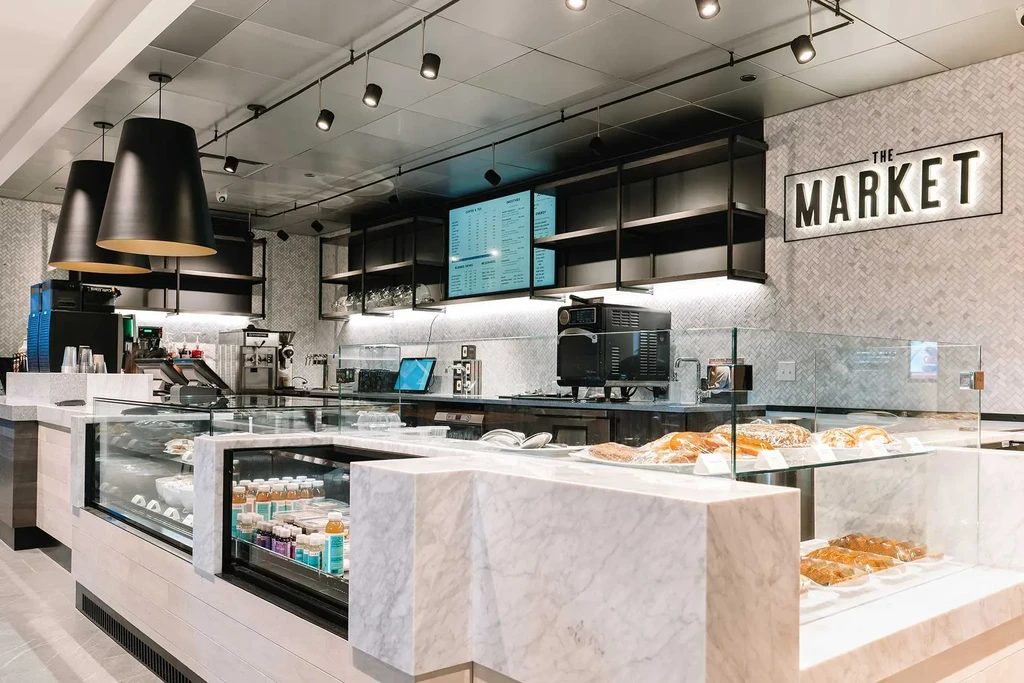 Modern cafe interior with "THE MARKET" sign above a marble counter.