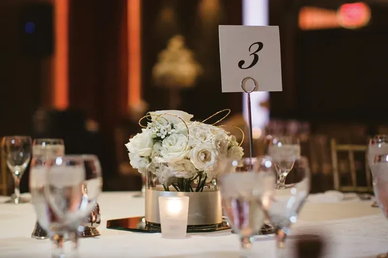 White rose centerpiece with gold wire, votive candle, table number 3.