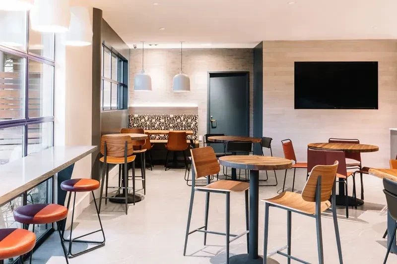 Stylish empty cafe interior with counter, high-top tables, and patterned booth.