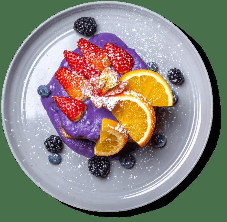 Dessert with purple cream, strawberries, blueberries, blackberries, and orange.