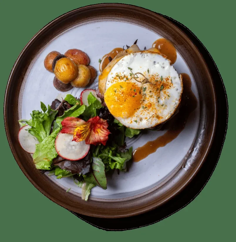 Plated gourmet brunch with sunny-side-up egg, roasted potatoes, and salad.