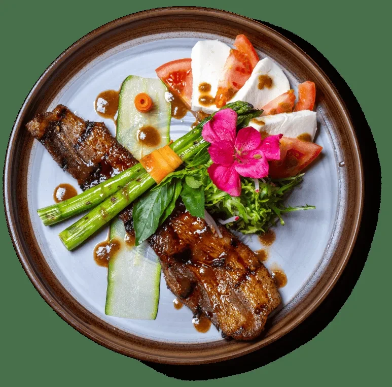 Professionally plated dish with glazed meat, asparagus, and Caprese elements.