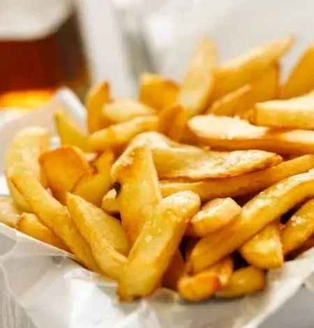 Crispy golden-brown thick-cut fries in a paper container.