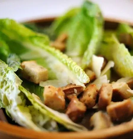 Crisp romaine lettuce and golden croutons in a wooden bowl.