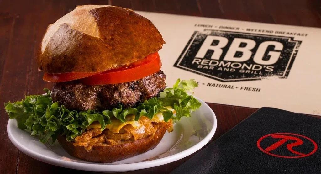 Pretzel bun burger with beef, melted cheese, and pulled pork.