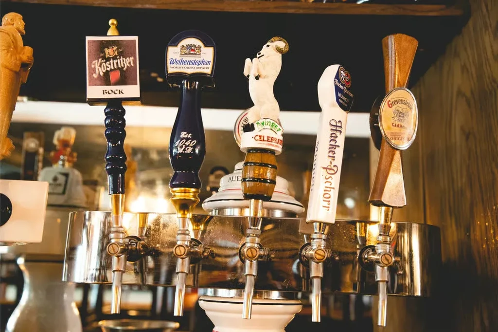 Close-up of five distinct beer tap handles on a polished draft system.