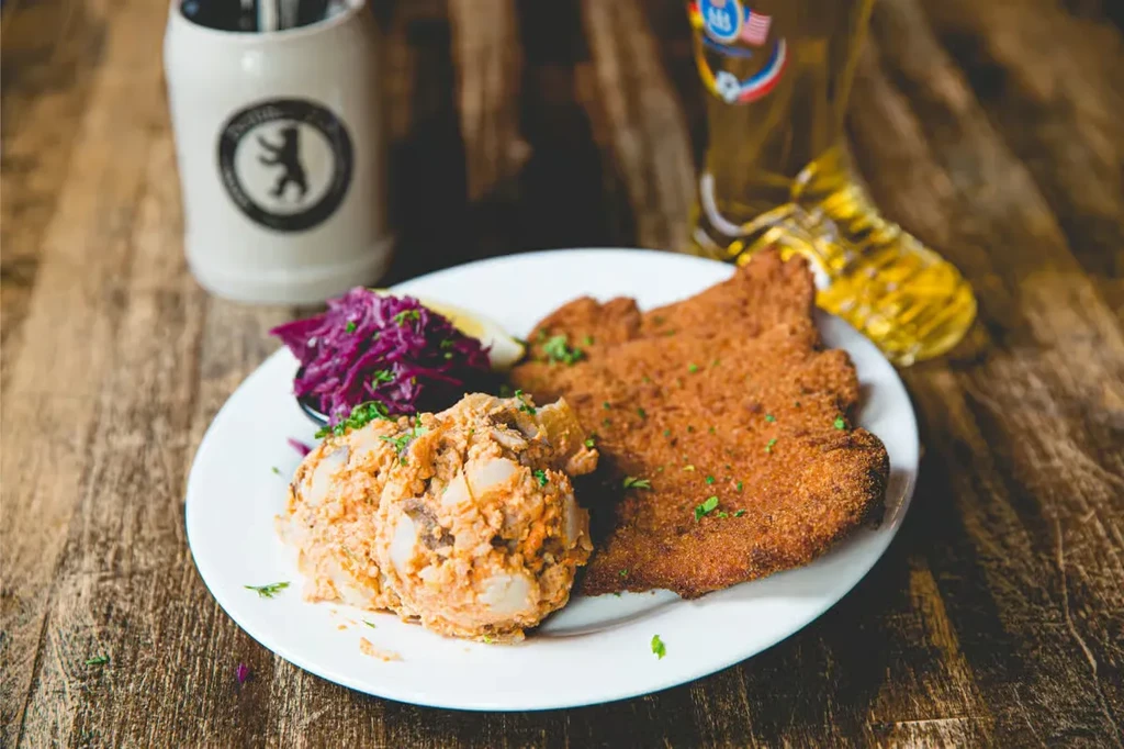 Close-up of schnitzel, potato salad, purple cabbage, and beer.