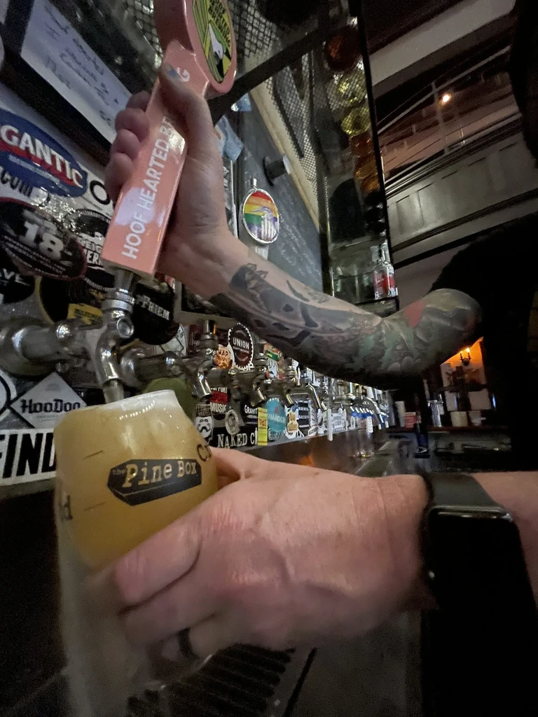 Tattooed hands pour Hoof Hearted beer from tap into glass.