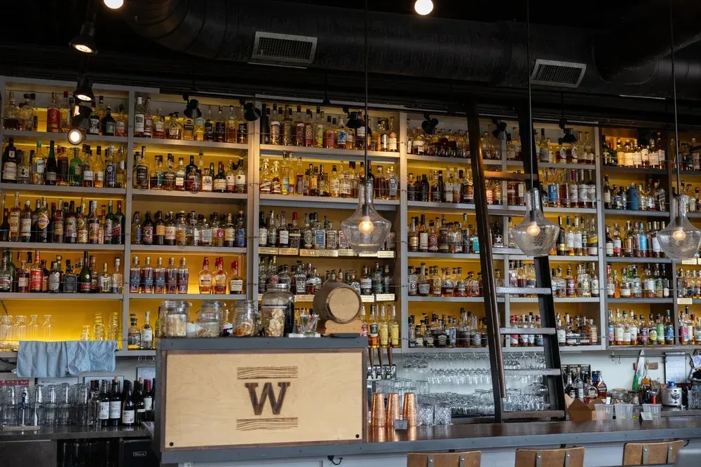 Well-stocked bar interior featuring hundreds of backlit liquor bottles.