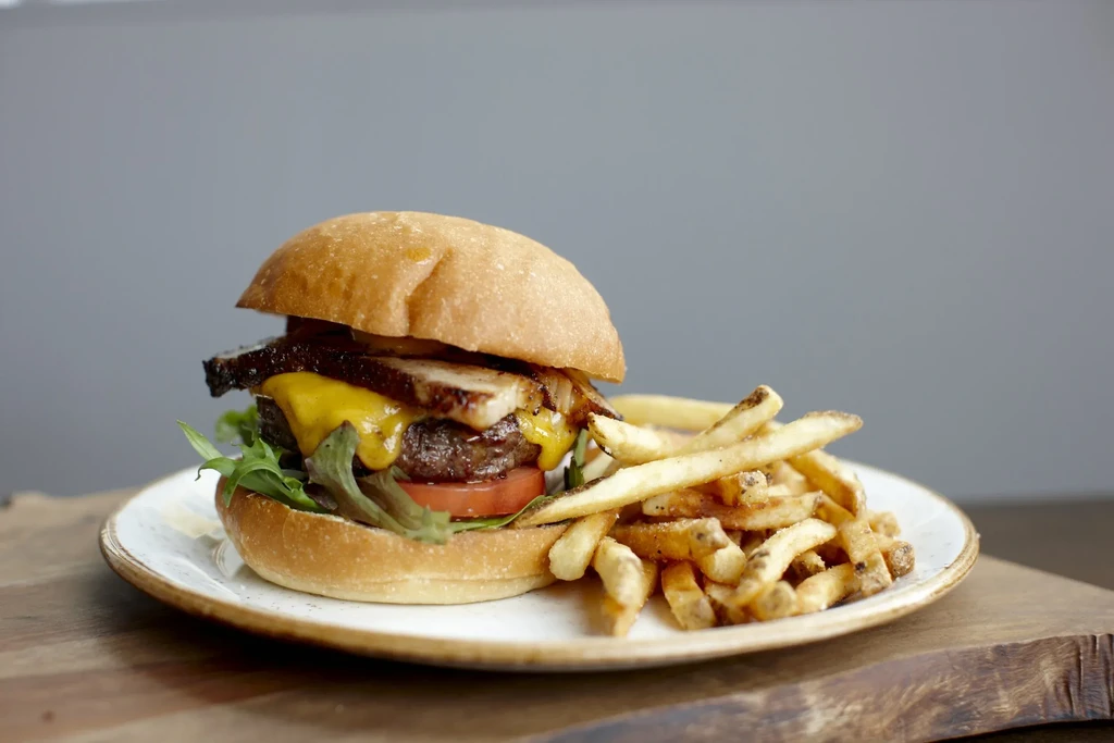 A plated burger with cheese, lettuce, tomato, and golden fries.