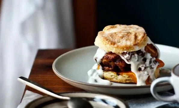 Close-up of a chicken biscuit sandwich smothered in creamy white sauce.