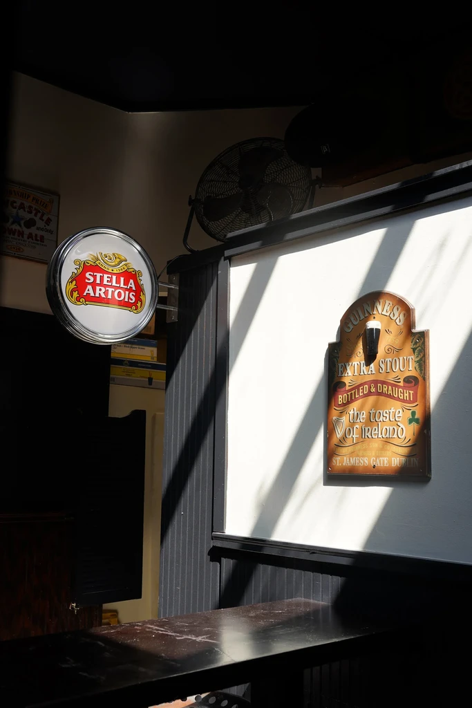 Stella Artois and Guinness signs dramatically lit in a bar.