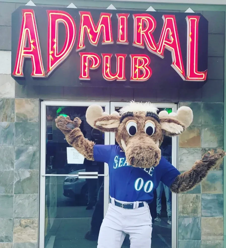 Costumed mascot in Seattle jersey stands at Admiral Pub entrance.