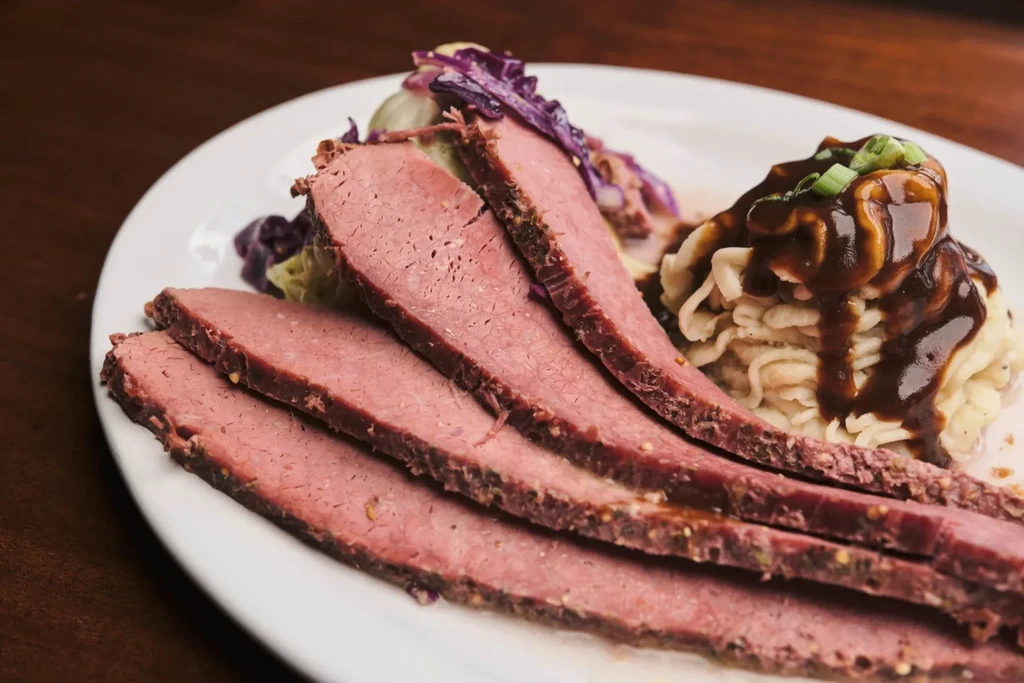 Sliced roast beef, mashed potatoes with gravy, and shredded cabbage.
