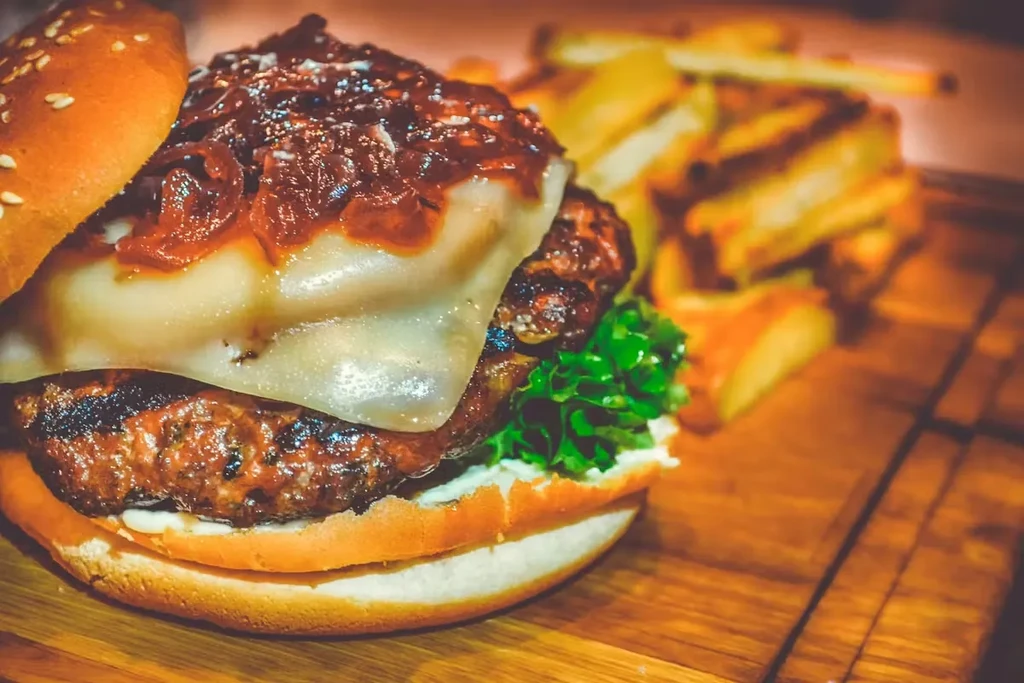 Gourmet burger with melted cheese, lettuce, and golden french fries.