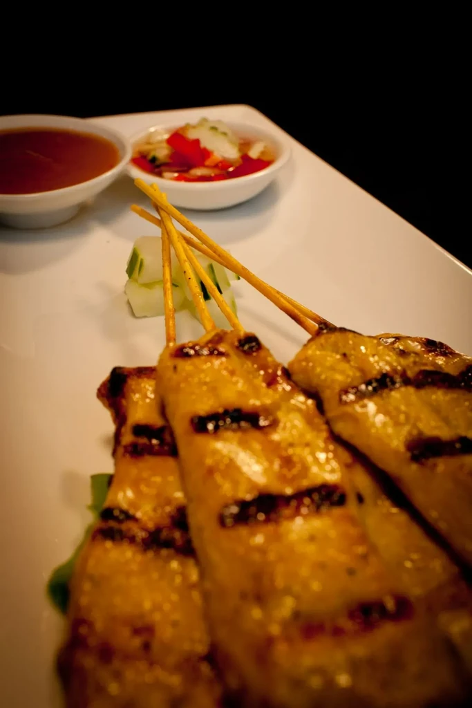 Golden grilled skewers with char marks and two dipping sauces.