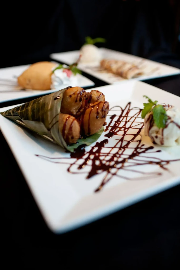 Fried bananas in banana leaf, vanilla ice cream, chocolate, and mint.