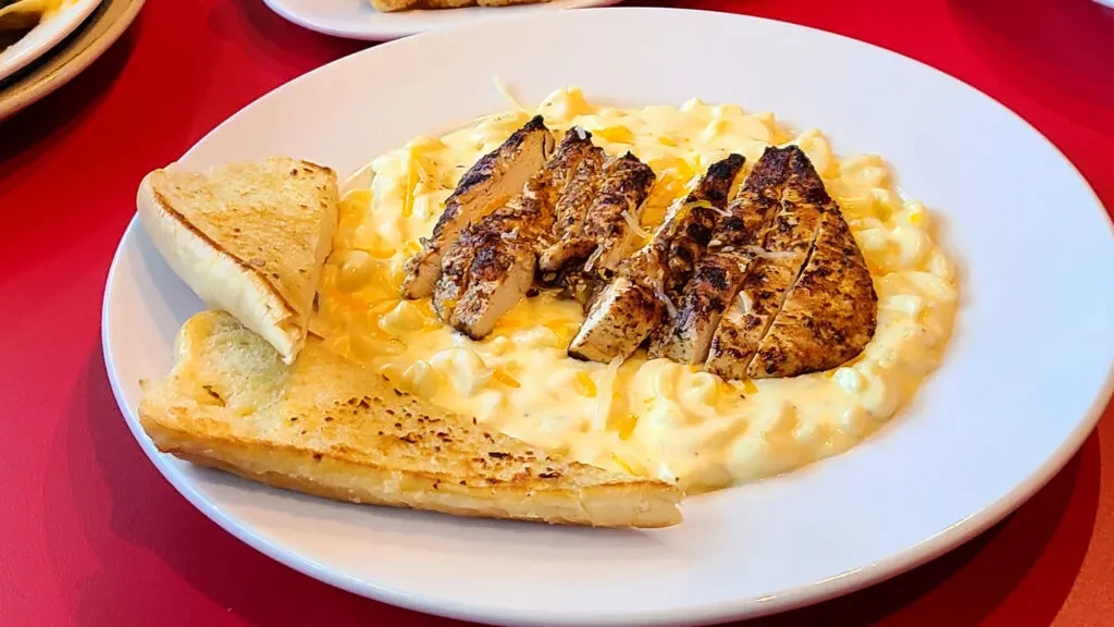 Grilled chicken, macaroni and cheese, and toasted bread on a plate.
