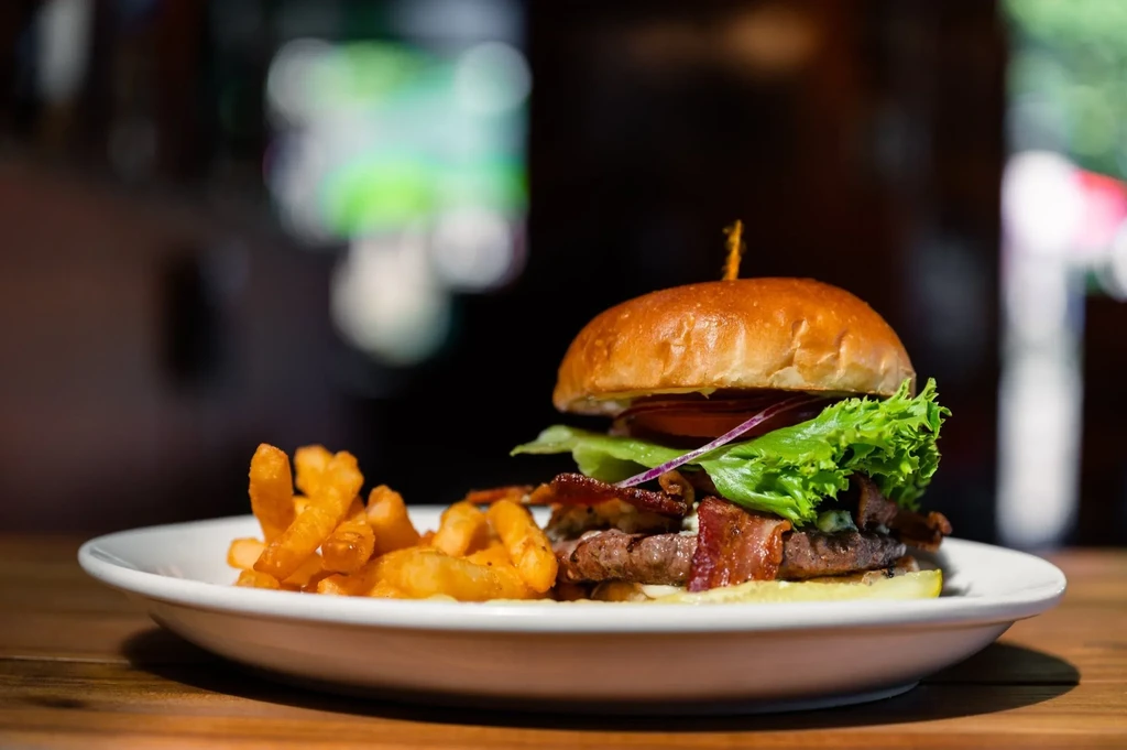 Close-up of a gourmet burger and french fries on a wooden table.