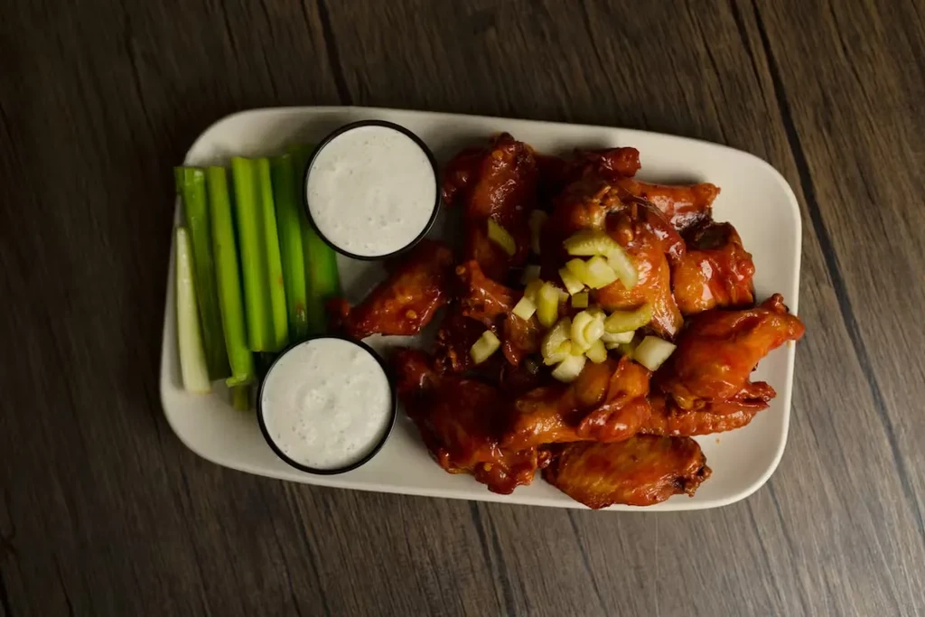 Buffalo chicken wings with celery sticks and blue cheese dipping sauce.