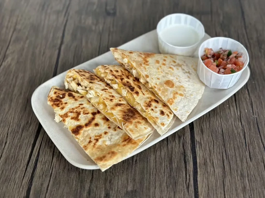 Four quesadilla wedges with sour cream and pico de gallo.