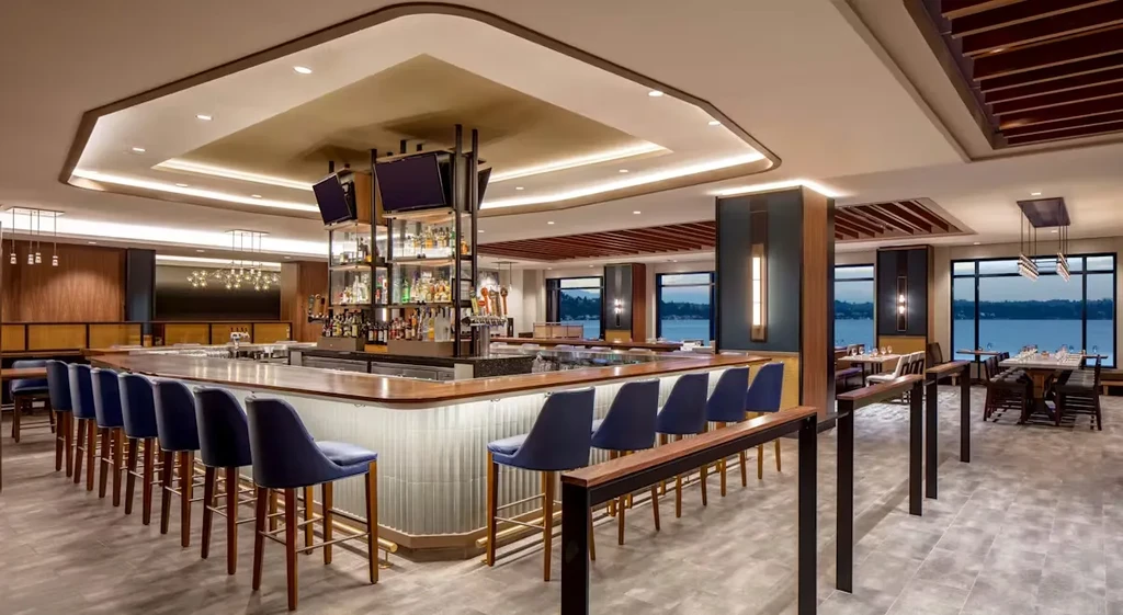 Empty modern bar with dark blue stools and a waterfront view.