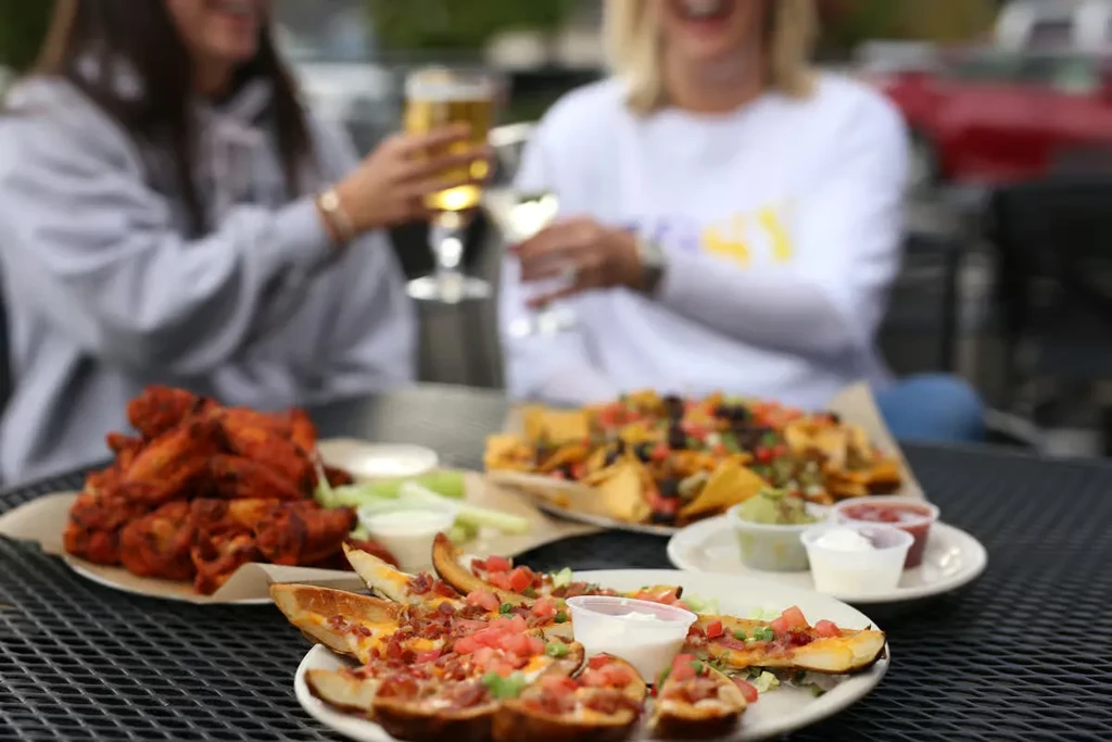 Loaded potato skins, buffalo wings, and nachos on a casual patio.