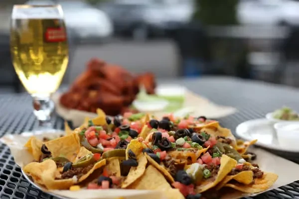 Loaded nachos with meat, cheese, and vegetables on an outdoor table.