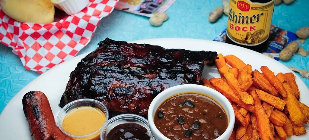 Barbecued ribs meal with hot dog, fries, baked beans, and sauces.