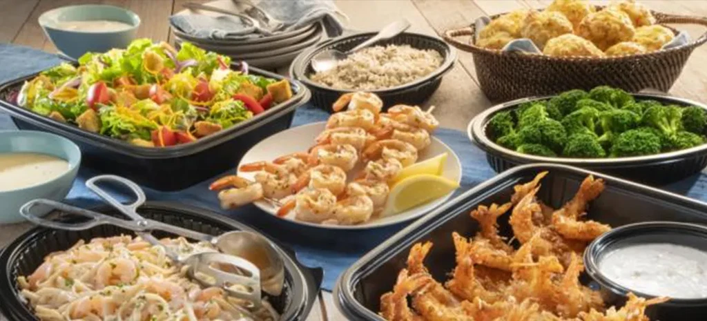 Rustic table laden with shrimp dishes, pasta, salad, and sides.