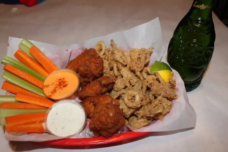 Mixed fried food, vegetables, and sauces in a red basket.