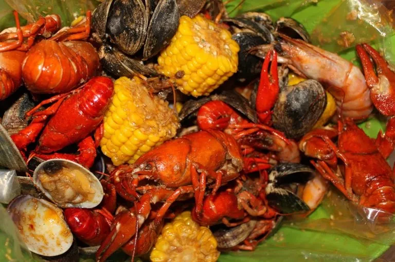 Close-up of a vibrant seafood boil with crawfish, mussels, clams, corn, and shrimp.