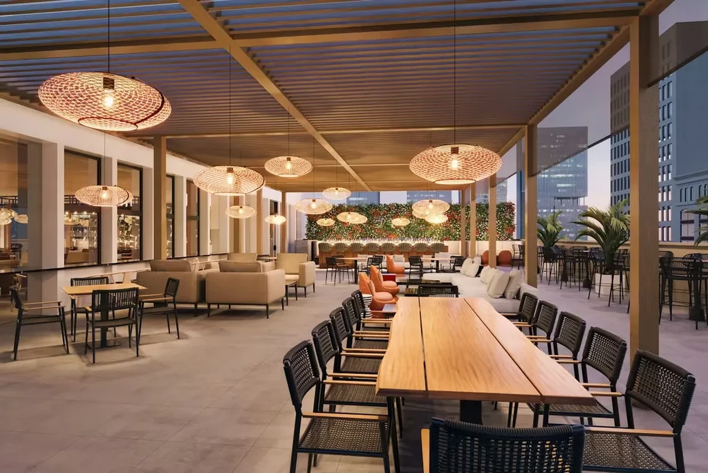 Modern open-air restaurant with varied seating, living wall, city view at dusk.