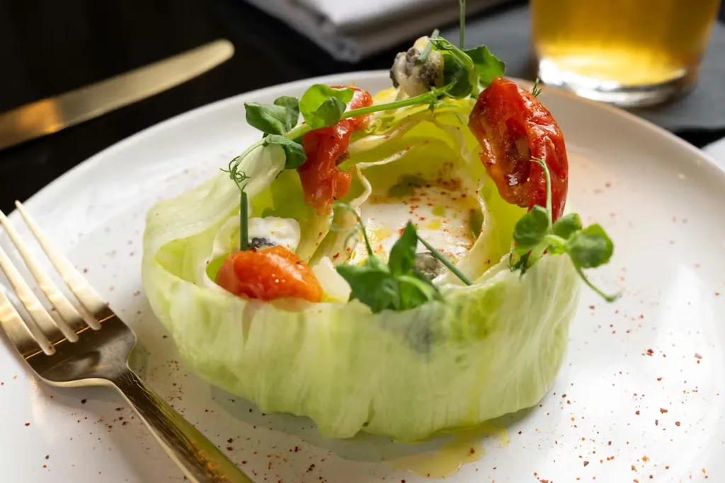 Elegant salad in a lettuce cup with tomatoes, blue cheese, and pea shoots.
