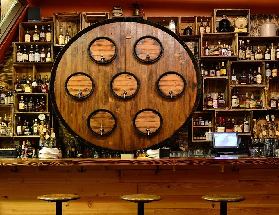 Well-stocked rustic bar with barrel taps and various liquor bottles.