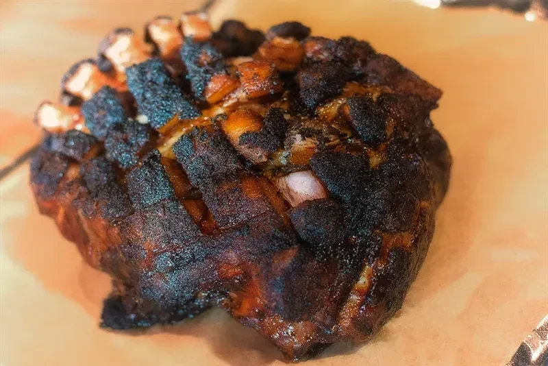 Dark, heavily crusted bone-in smoked meat on butcher paper.