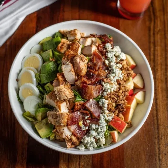 Overhead: vibrant salad with chicken, bacon, blue cheese, avocado.