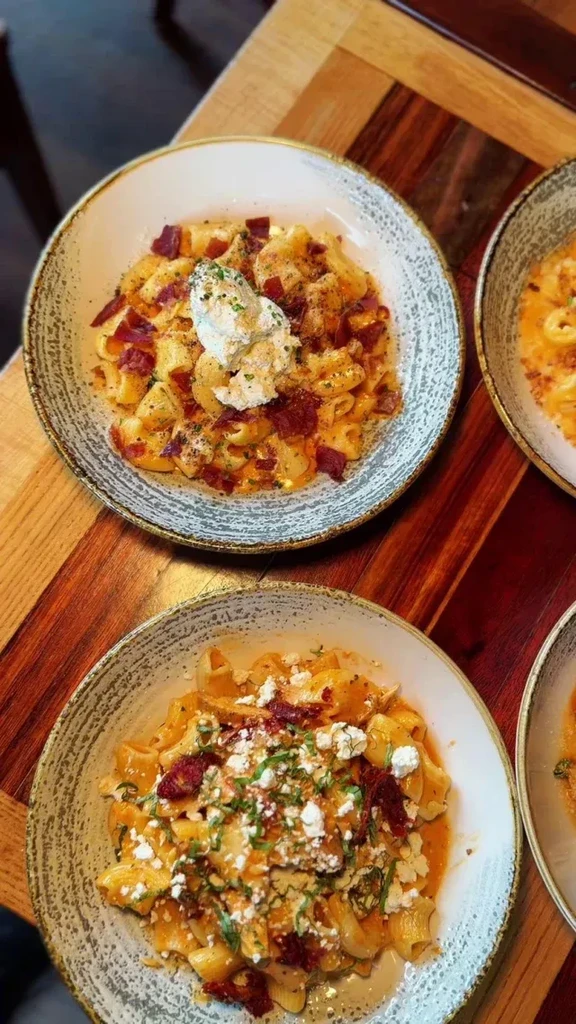 Top-down view of two distinct pasta dishes on a wooden table.